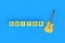 Word guitar on cubes near acoustic instrument on blue background
