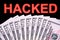 The word `Hacked` at the blurred background and money in front. Selective focus
