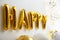 Word HAPPY made of golden balloon letters on wall