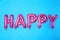 Word HAPPY made of pink foil balloon letters on blue background