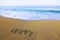 Word HAPPY written on beach sand a