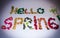 The word Hello spring lined with faux flowers on white background