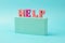 The word help from wooden bright letters on the podium on a pale blue background