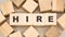 Word hire with black letters on toy wooden cubes on table