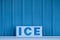 Word ICE in capital letters on sign in front of cold blue metal