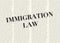 The word IMMIGRATION LAW written and highlighted in front of blurred text columns on background of light yellow color