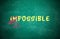 Word IMPOSSIBLE with crossed out letters IM written on green chalkboard. Motivation and positivity