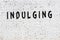 Word indulging painted on white brick wall