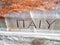 The word Italy carved into marble on a sarcophagus casket inside a church