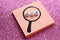 word job of plastic beads in a drawn magnifier on stickers on a brilliant pink background.