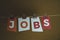 The word Jobs written on colorful note papers on board background. Employment concept. Job search