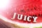 The word Juicy made of wooden letters on watermelon
