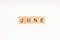 Word JUNE made of wooden blocks on white background. Month of year