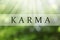 Word KARMA on blurred green background, bokeh effect