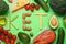 Word Keto made with products surrounded by different food on light green background, flat lay