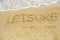 Word leisure written on the beach sand