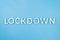 The word lockdown laid with brushed aluminium metal letters on blue background