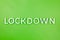 The word lockdown laid with brushed aluminium metal letters on green background