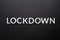 The word lockdown laid with silver metal letters on flat black background in directly above perspective