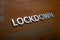 The word lockdown laid with silver metal letters on flat rusted steel sheet background in slanted diagonal perspective