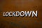 The word lockdown laid with silver metal letters on flat rusted steel sheet background in slanted linear perspective