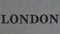 The word `London` is printed on a piece of paper, close-up