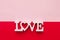 The word love consists of wooden letters located on a pink and red background