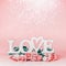 Word LOVE on pastel pink background with lovely roses bunch and bokeh , front view. Creative female holidays layout