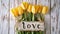 the word "Love" placed next to a beautifully arranged bouquet of tulips on a light background, blending modern