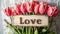 the word "Love" placed next to a beautifully arranged bouquet of tulips on a light background, blending modern
