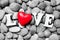 The word Love with red heart on pebble stones