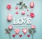 Word love with roses, hearts and decoration ribbons on pastel blue background, top view. Valentines day or abstract love concept