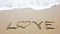 Word love on the sand that wiped off by sea wave