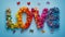 Word \\\'LOVE\\\' spelled out with multicolored flowers butterflies blue background. Flat lay, copy space