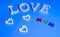 Word love in white and also three white hearts and colored word mom over blue background