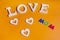 Word love in white and also three white hearts and colored word mom over orange background
