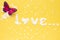 Word love with white flower petals on yellow background