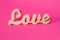 Word love, wooden letters on pink paper. Valentine& x27;s day background. Lovestory or wedding decor.