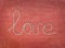 Word love written from rope on red canvas background. Text elements with shadow on pink cotton fabric texture. Close up, top view