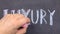 Word LUXURY, written by hand in chalk on a blackboard.