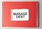 The word Manage Debt on torn paper on red notepad