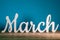 The word MARCH - wooden text at dark blue background. Spring concept