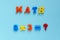 Word `math` and multiplication of plastic magnetic letters on blue background