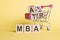 The word MBA - Master of Business Administration, on wooden cubes, on a yellow background with a shopping trolley