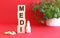 The word MEDI is made of wooden cubes on a red background. Medical concept