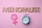 Word Menopause made of wooden letters, female gender sign and alarm clock on pink background, flat lay