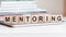 The word mentoring is written on wooden cubes, concept