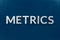 The word metrics laid with silver metal letters on classic blue surface