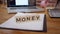 Word money is folded with hands made of wooden cubes with letters on the desktop. Concept of wealth and success.