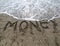 Word MONEY on the sand and wave that is erasing the text symbol